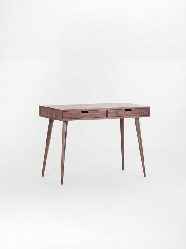 Empty HEIM 105 small wooden desk in solid walnut, angled view with two wooden drawer fronts