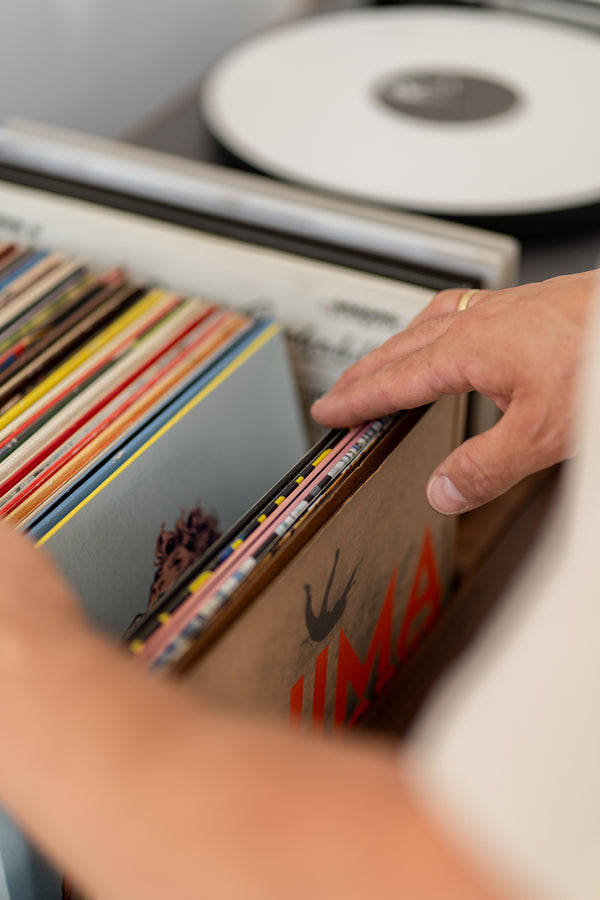  Hands flipping through vinyl records in a box.