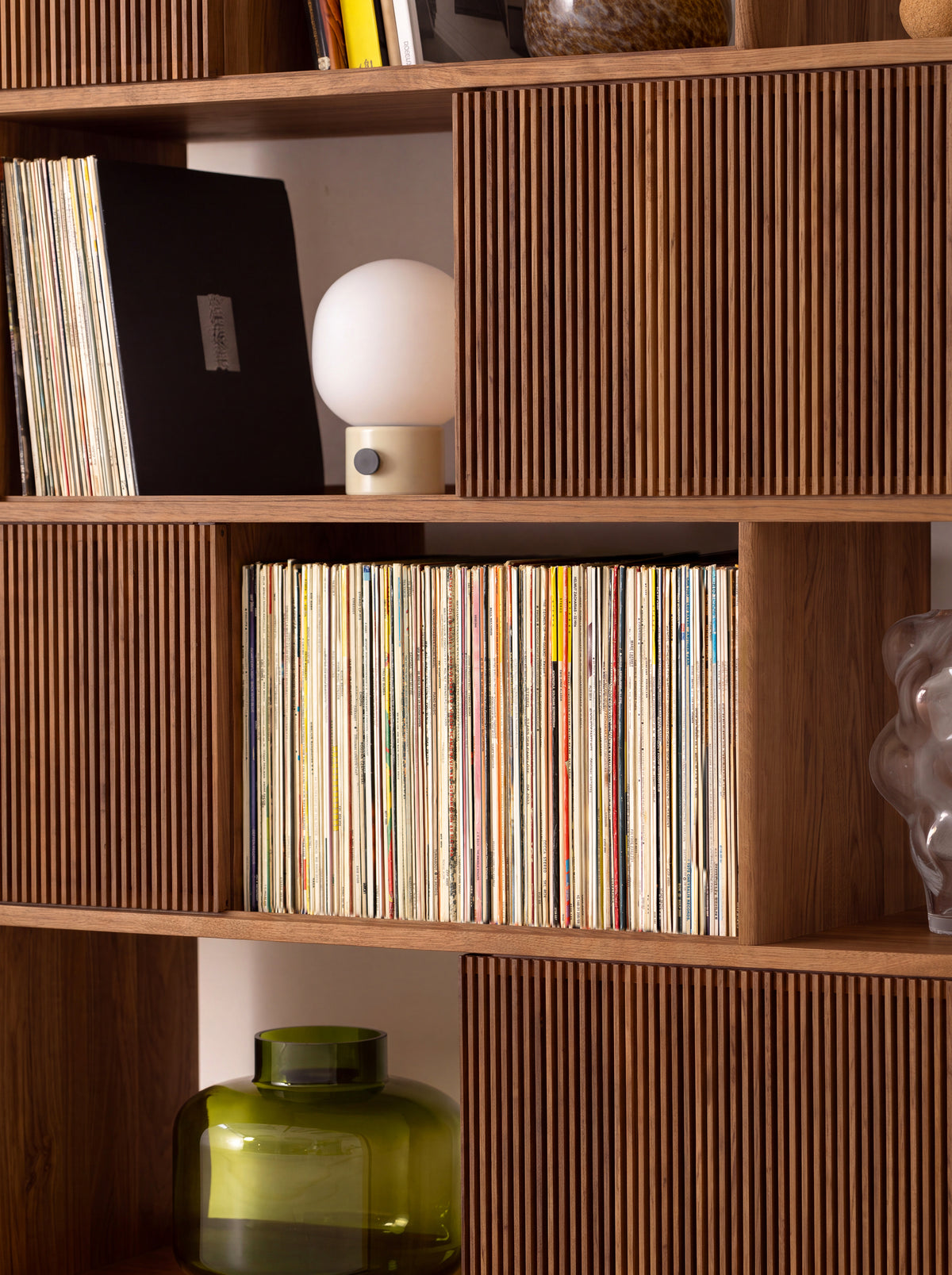 A long row of records on MOLL DUO in solid walnut, shown close up with a table lamp and slatted fronts
