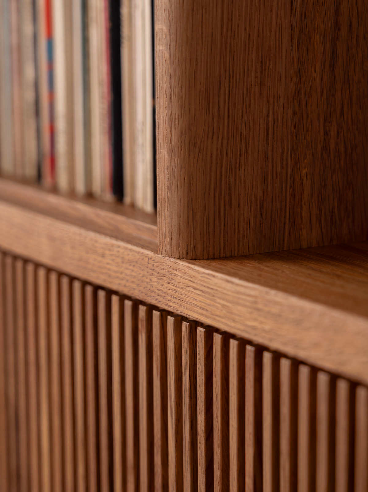 MOLL DUO in solid walnut, close-up of the shelf edge and upright above a slatted front, with records behind