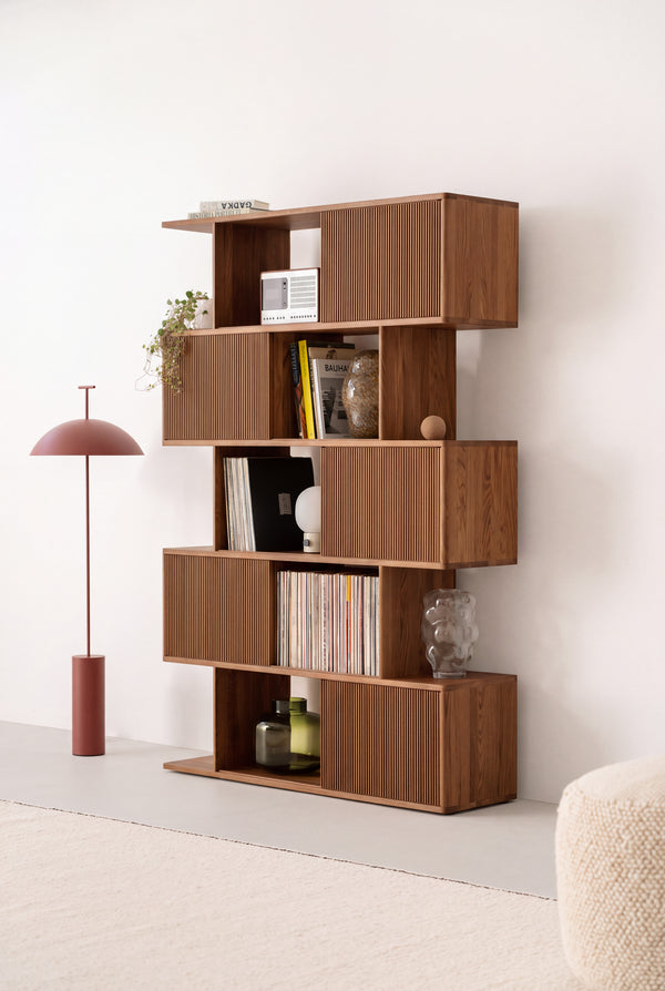 MOLL DUO tall bookcase in solid walnut, viewed at an angle in a bright room with slatted fronts, books, records and a radio