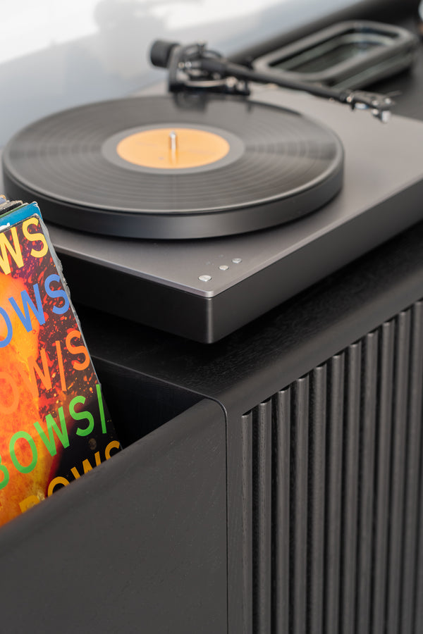 Close-up of a turntable with a vinyl record, and a colorful album cover partially visible.