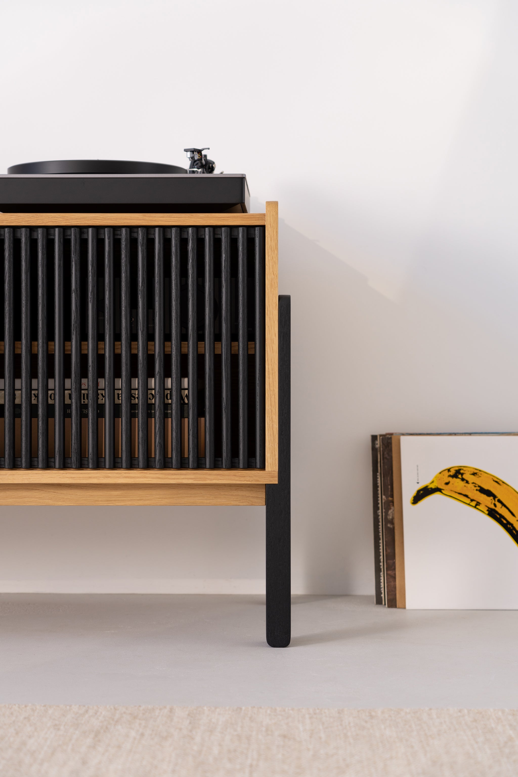 Turntable on a wooden cabinet with vinyl records stacked beside it.