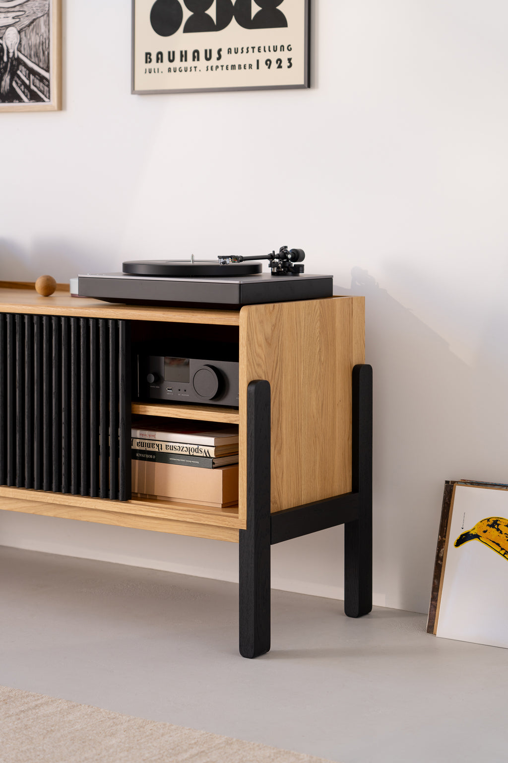 Wooden cabinet with turntable, books, and framed art on the wall.