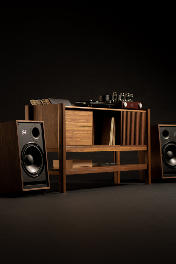 Vintage-style wooden cabinet with a turntable and records, flanked by two speakers, set against a dark background.