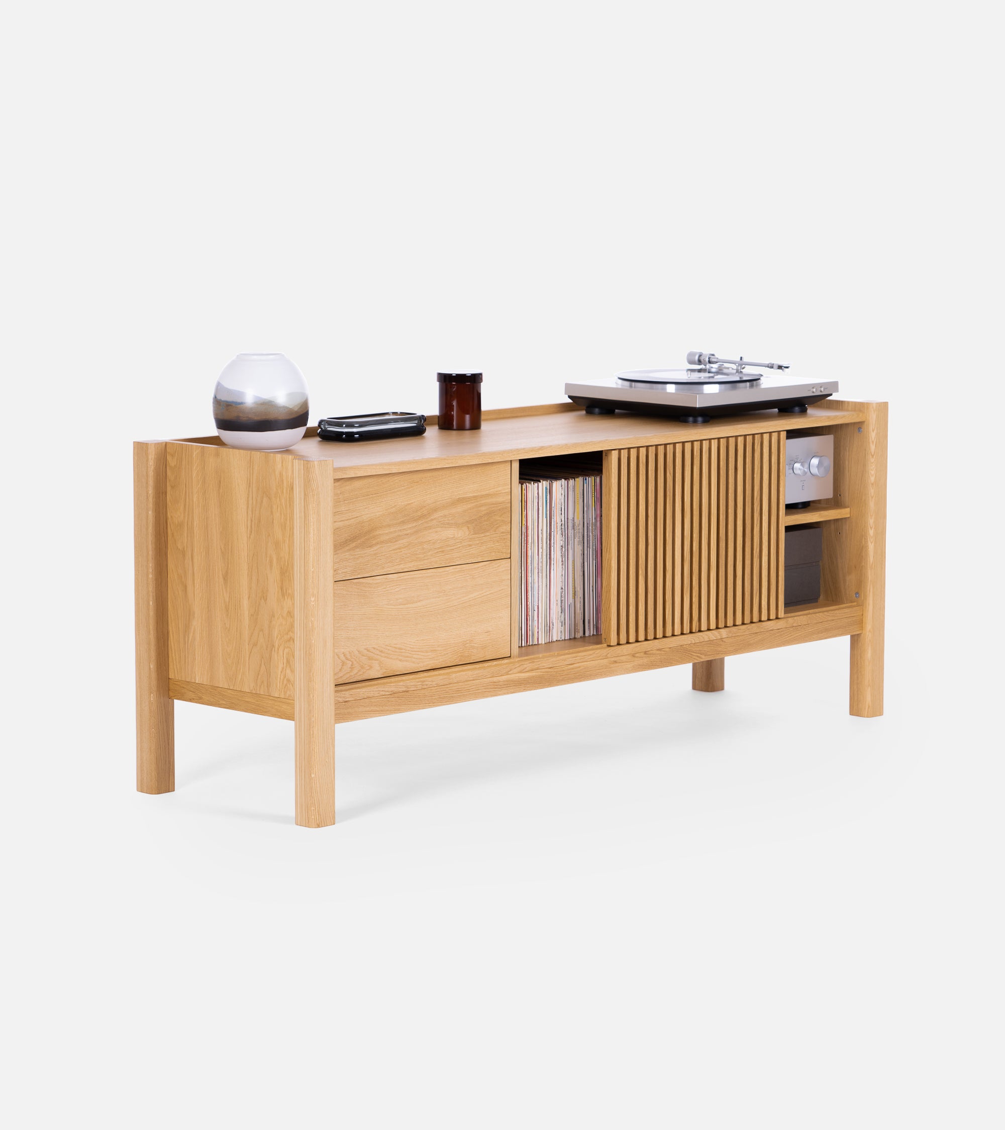 Oak sideboard with vinyl records, a turntable, and decor items on top. Features drawers and a slatted sliding door.