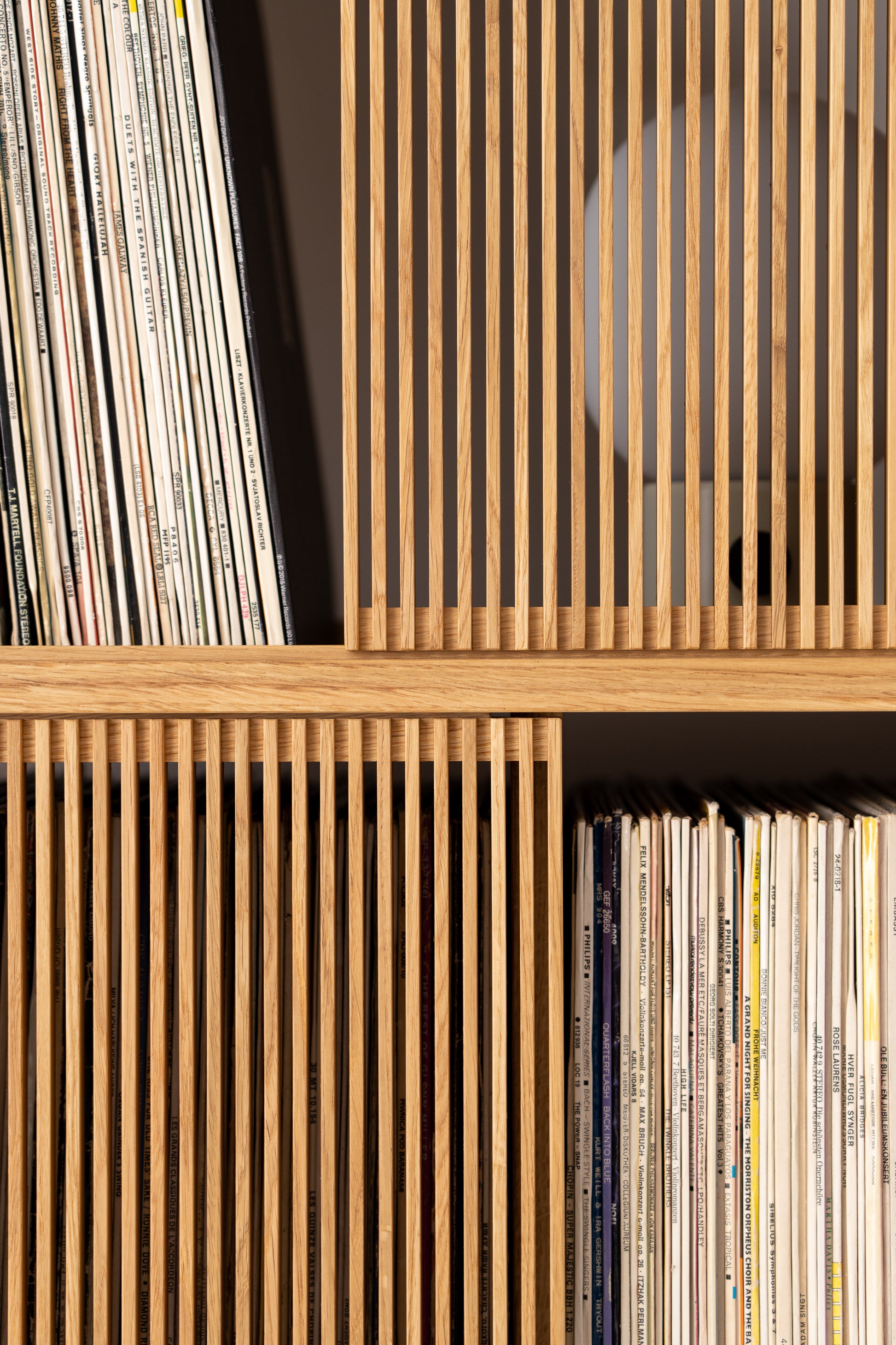 Wooden shelves filled with vertically stacked vinyl records.
