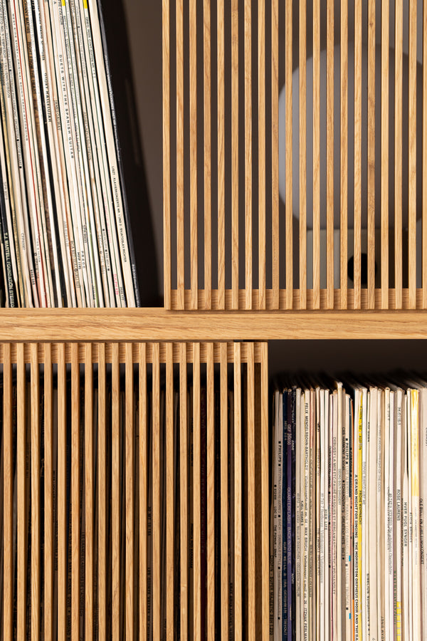 Wooden shelves filled with vertically stacked vinyl records.