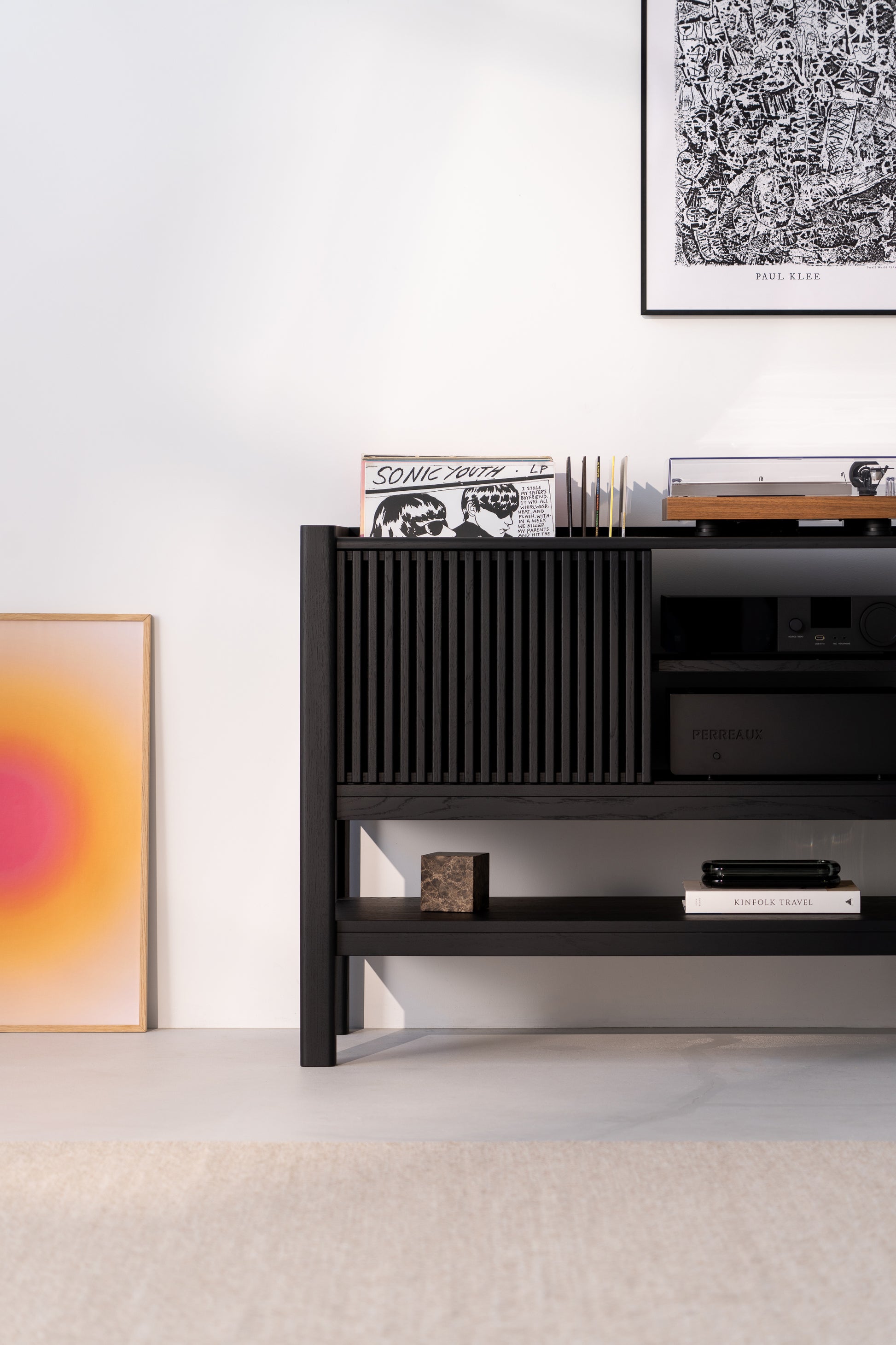 Sleek black shelf with records, artworks, and a turntable in a modern, minimalist space.