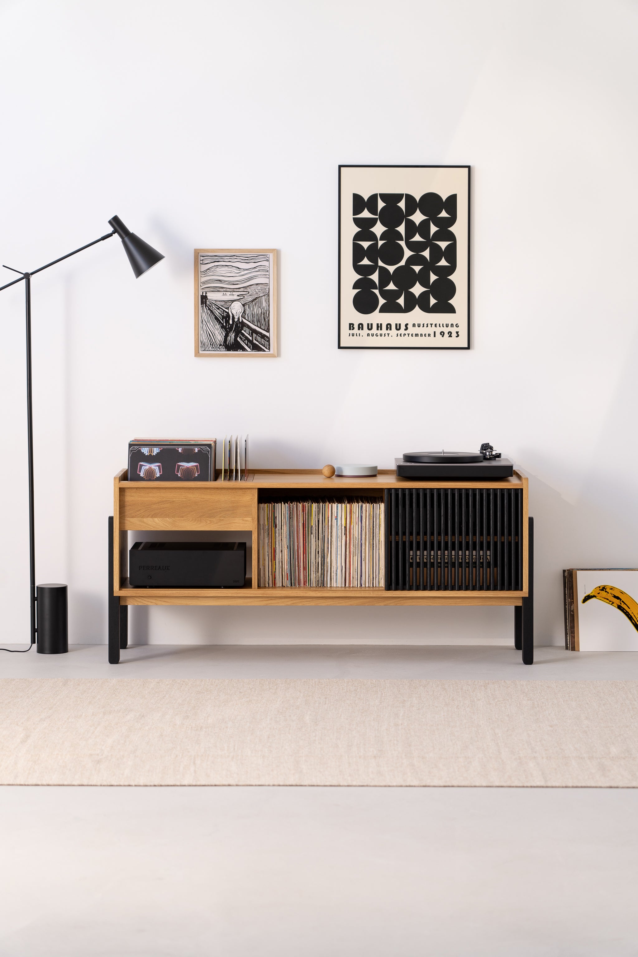 Stylish room with a wooden console, vinyl records, a turntable, modern art, and a floor lamp.