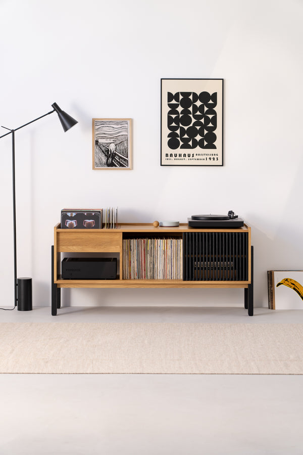 Stylish room with a wooden console, vinyl records, a turntable, modern art, and a floor lamp.