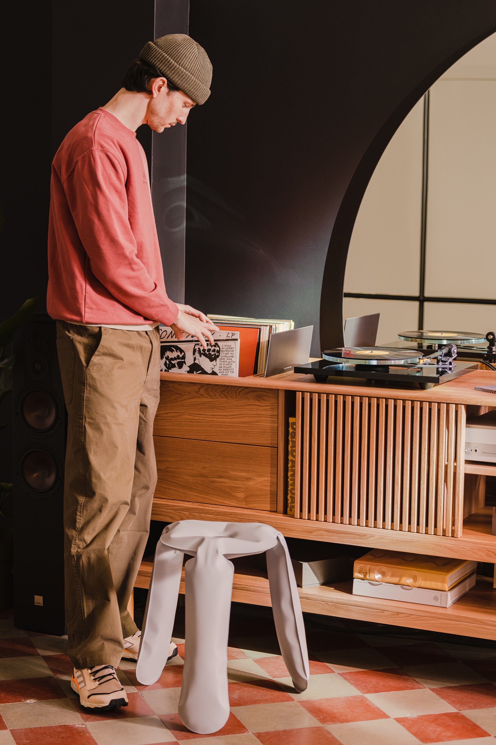 Person browsing vinyl records next to a modern record player in a cozy room.