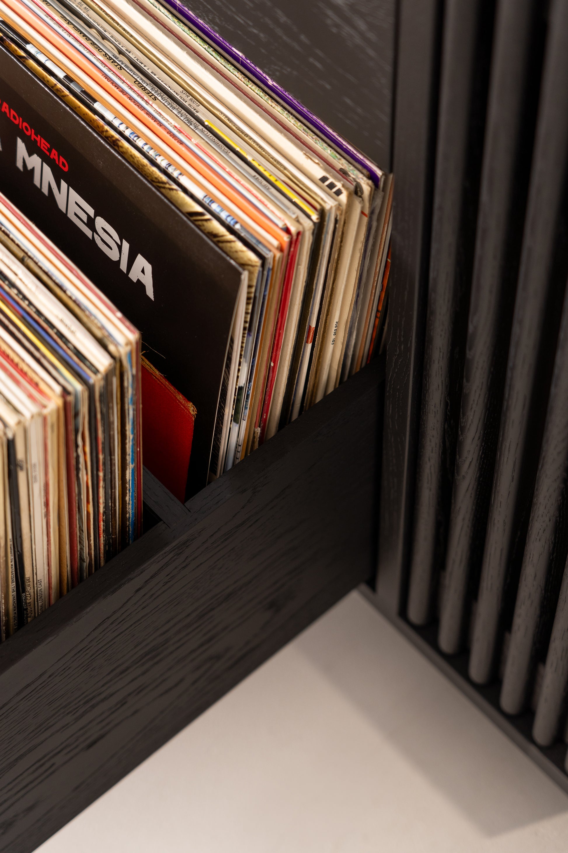 Vinyl records stored vertically in a dark wooden shelf.