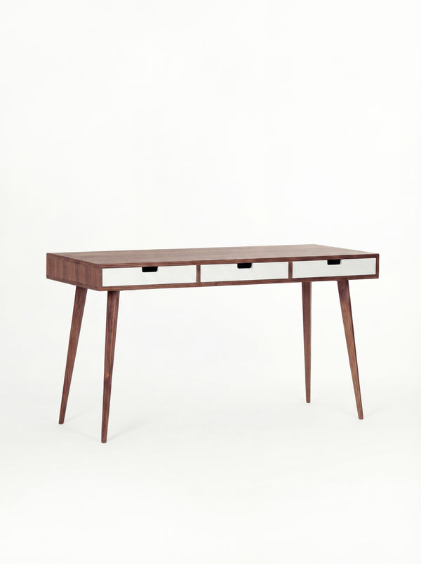 HEIM 140 desk in solid walnut with three white drawer fronts, empty and shown at a three-quarter angle