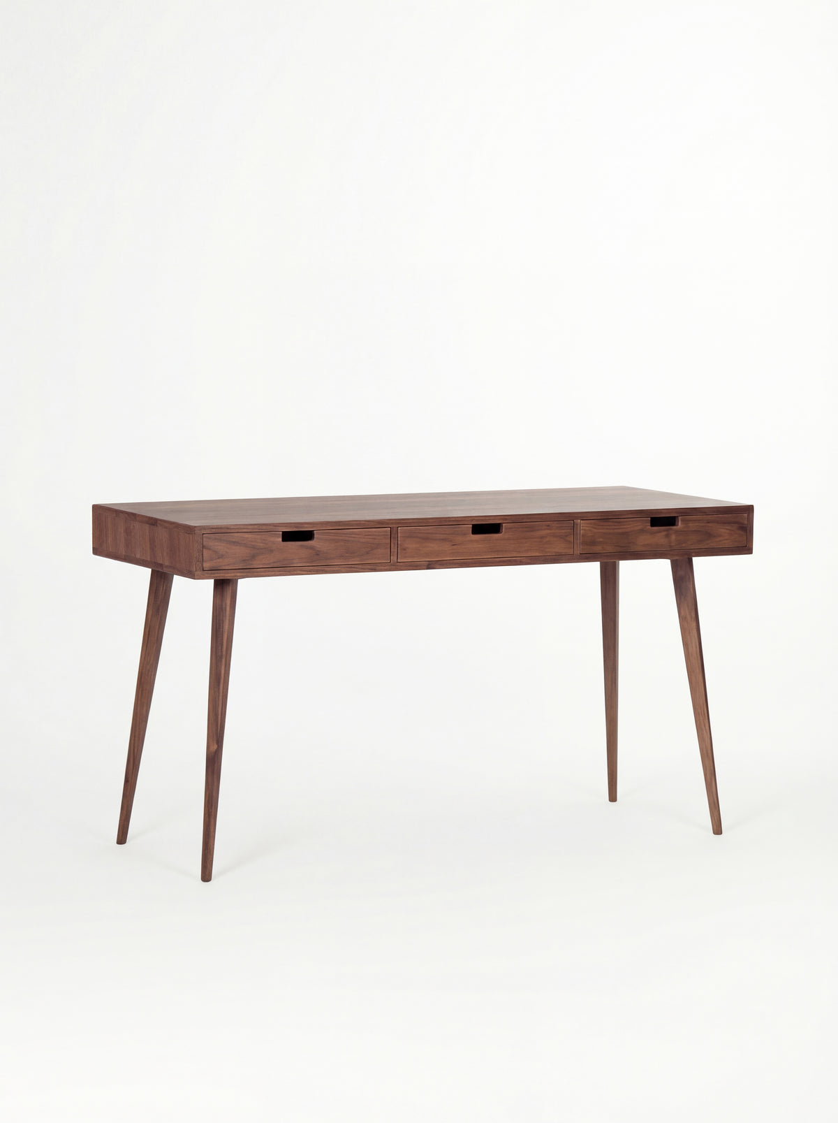 HEIM 140 solid walnut desk with drawers, shown at an angle with three cut-out grips and an empty top