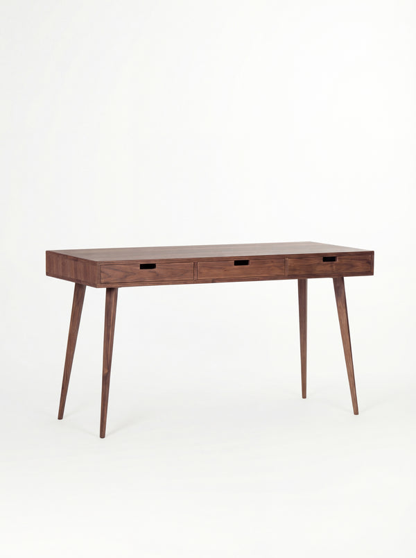 HEIM 140 solid walnut desk with drawers, shown at an angle with three cut-out grips and an empty top
