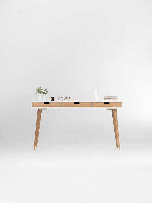 Front view of the HEIM 140 white desk in solid oak, with three natural oak drawer fronts and decor on top