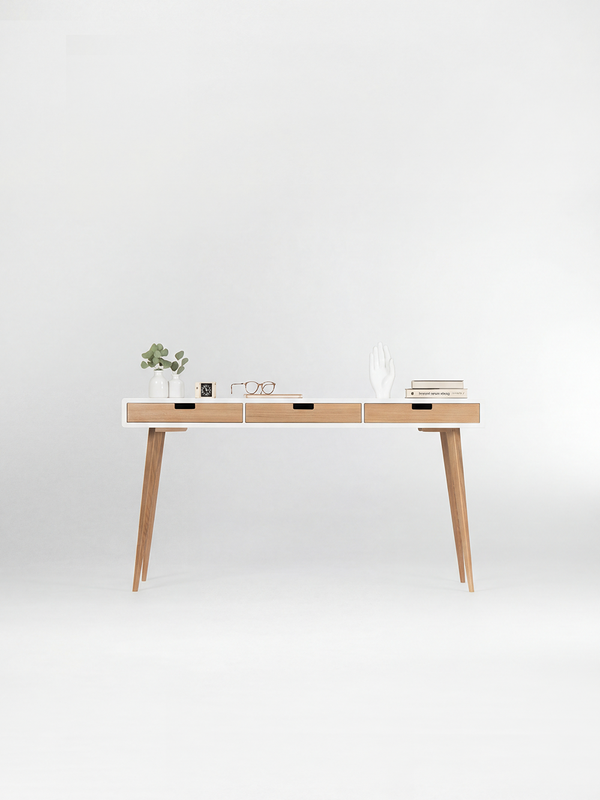 Front view of the HEIM 140 white desk in solid oak, with three natural oak drawer fronts and decor on top