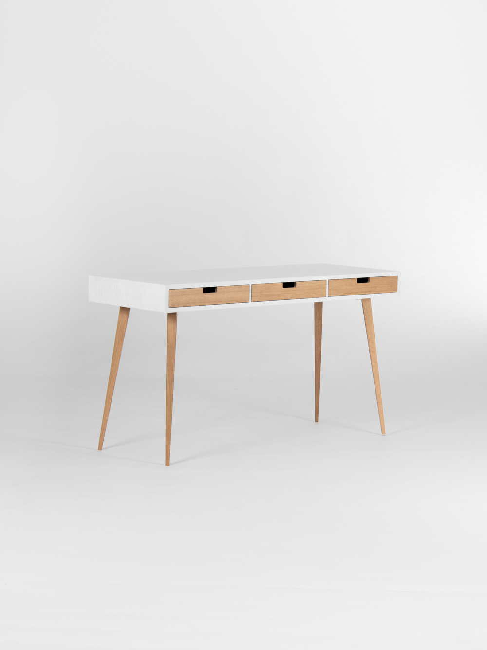 Three natural oak drawer fronts on the HEIM 140 desk in solid oak, shown empty at an angle with a white body