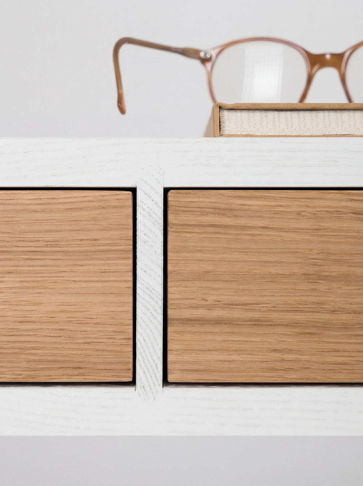 Macro view of the HEIM 140 desk in oak wood, with two oak drawer fronts and visible grain in the white divider