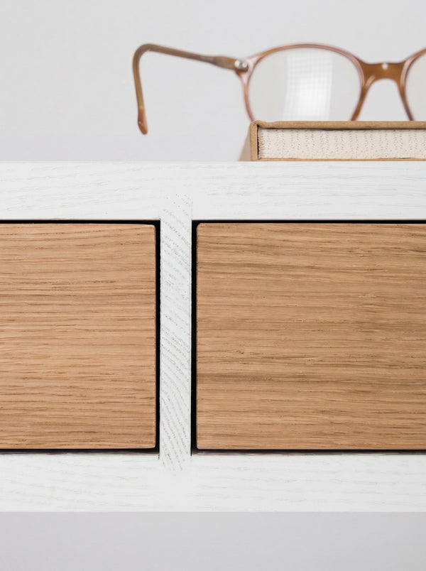 Macro view of the HEIM 140 desk in oak wood, with two oak drawer fronts and visible grain in the white divider