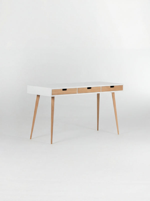 HEIM 140 desk in oak wood, empty and angled to show its white body, three natural oak drawer fronts and oak legs