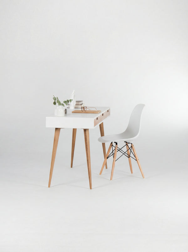 HEIM 140 white writing desk in oak wood, viewed from the short end with a shell chair, eucalyptus and books