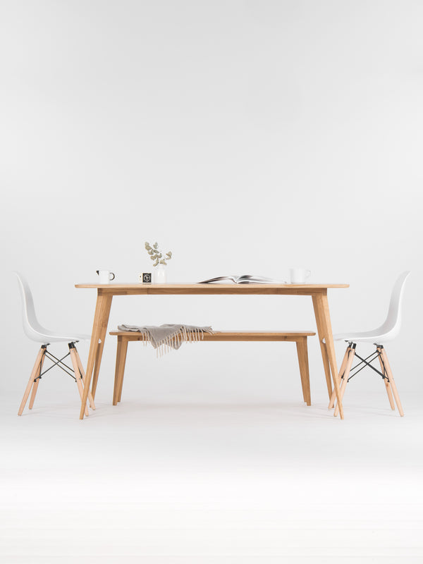 Minimalist dining area with a wooden table, chairs, a vase, and an open book.