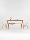 YRKE modern dining table in solid oak with the bench tucked underneath, flanked by two white chairs, mug and magazine on top