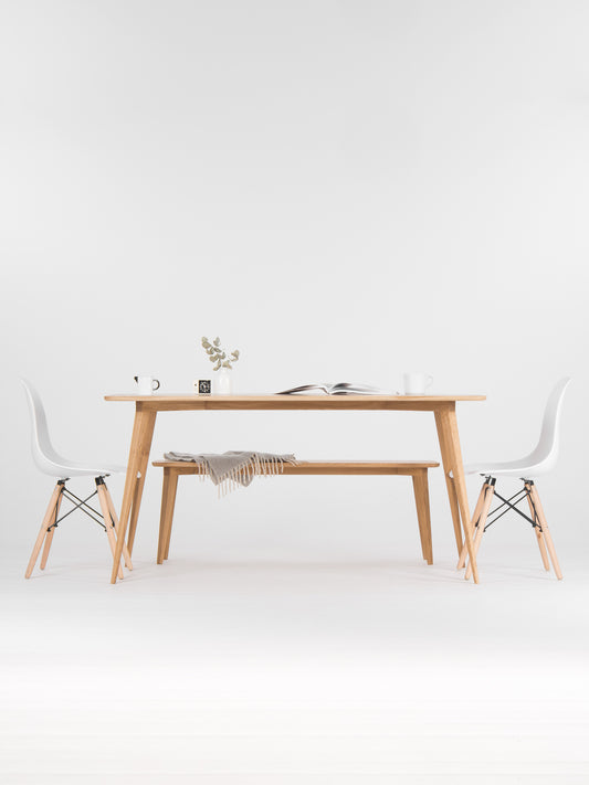 Minimalist dining area with a wooden table, chairs, a vase, and an open book.