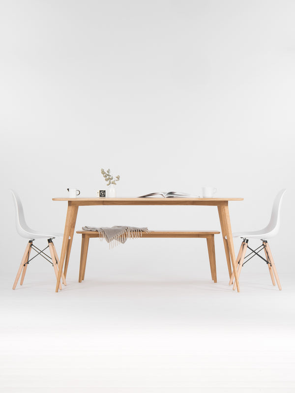 Minimalist dining area with a wooden table, chairs, a vase, and an open book.