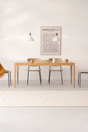 HYGG solid oak minimalist dining table facing front in a bright dining room with chairs, Bauhaus poster and two pendant lamps