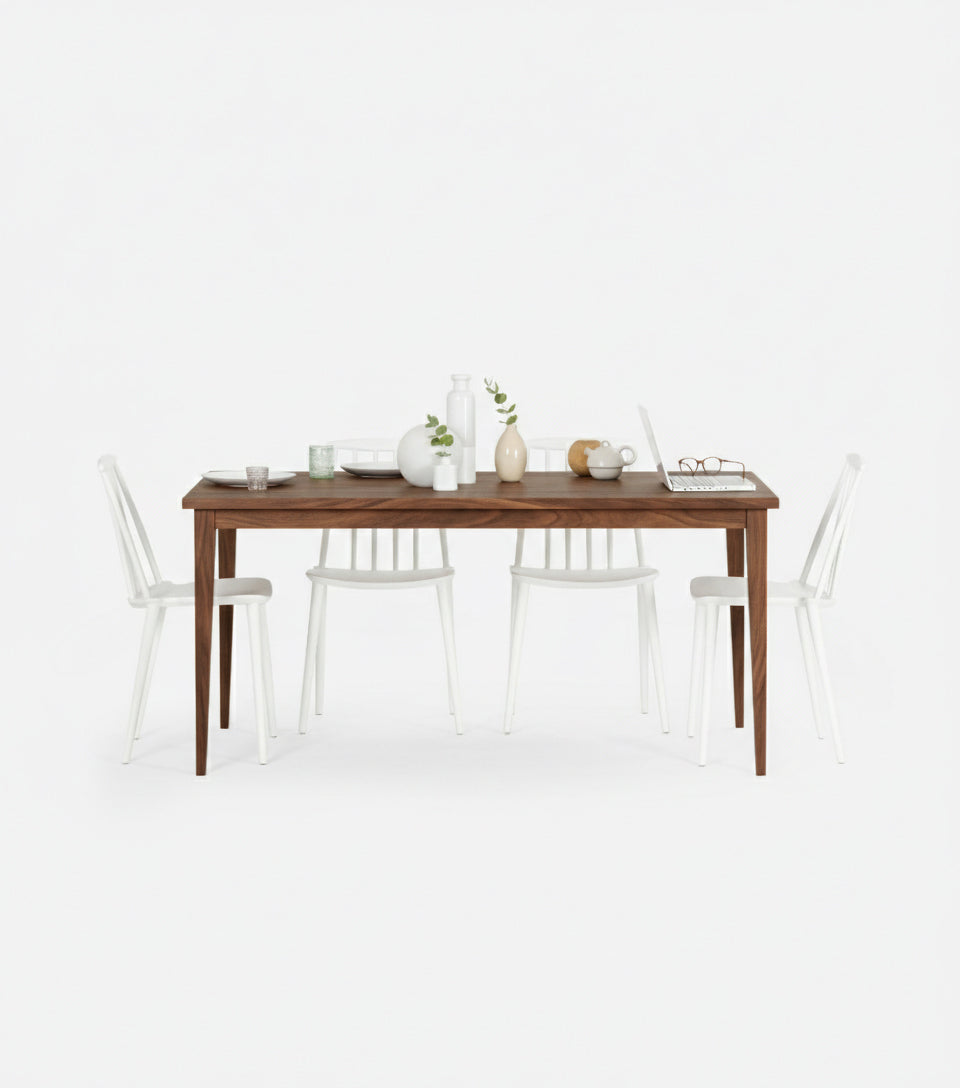 Wooden dining table with white chairs, decorated with vases, cups, a laptop, and a pair of glasses.