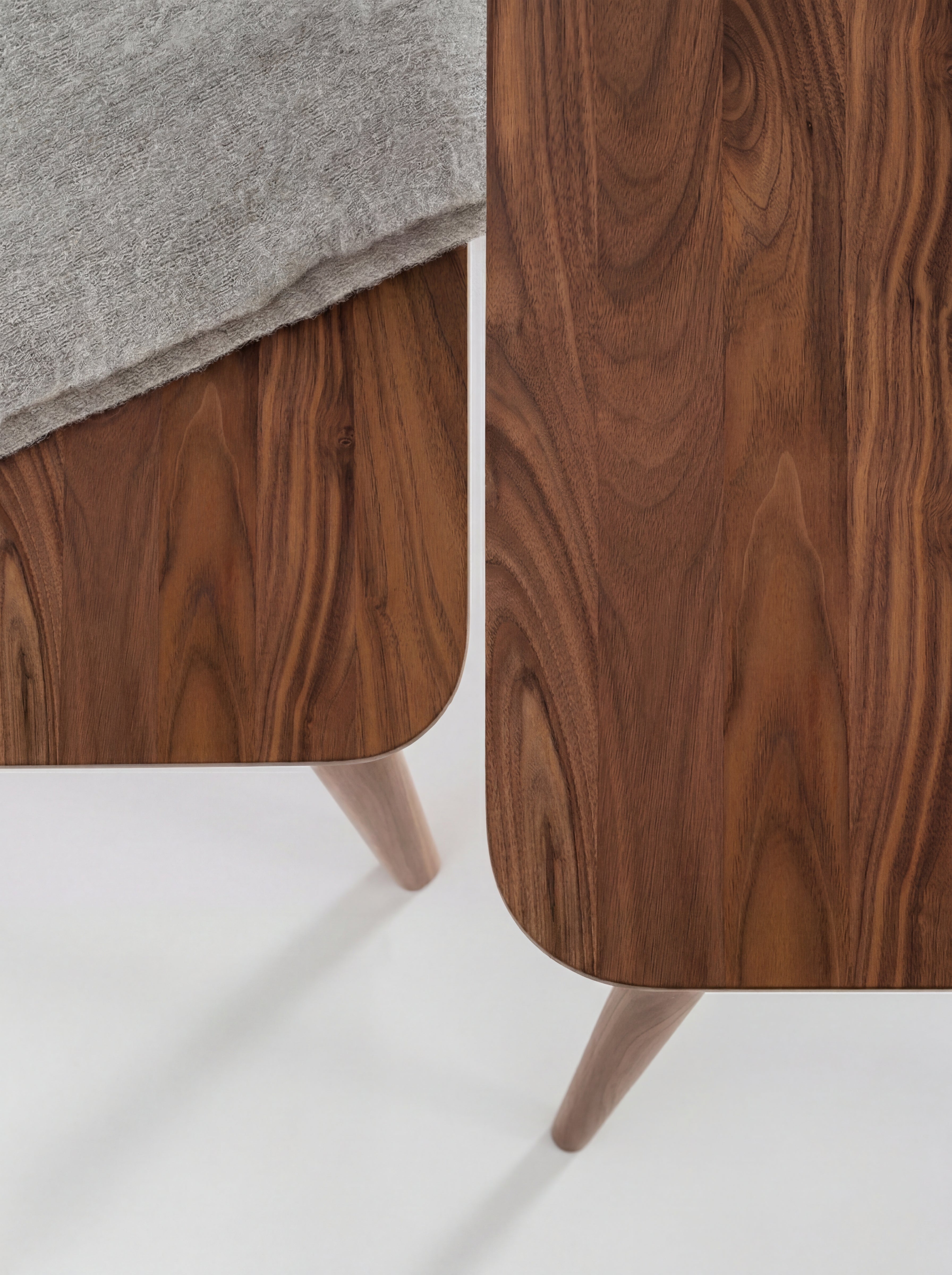 Two wooden tables with smooth, curved edges and a gray fabric draped over one table.