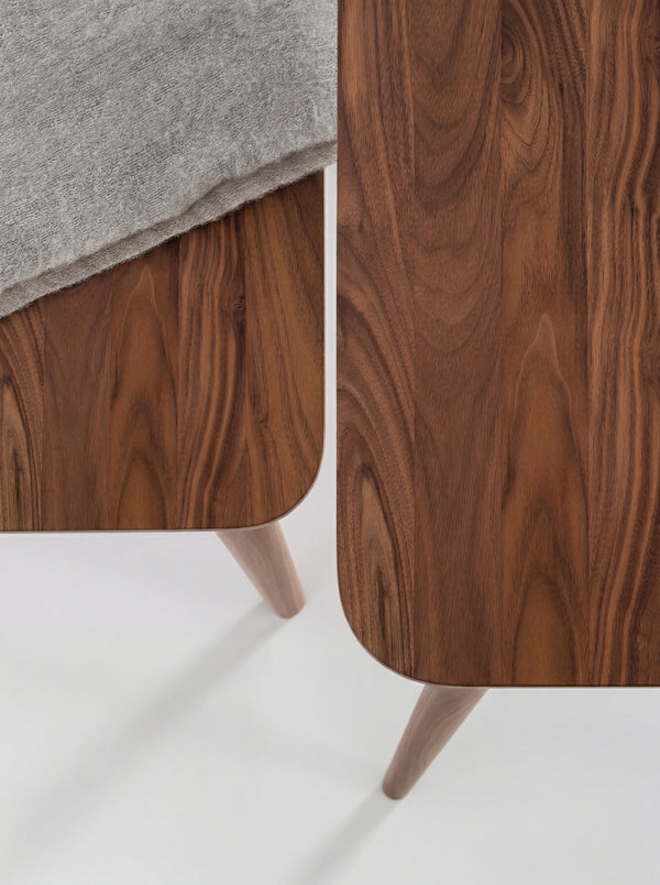 Two wooden tables with smooth, curved edges and a gray fabric draped over one table.