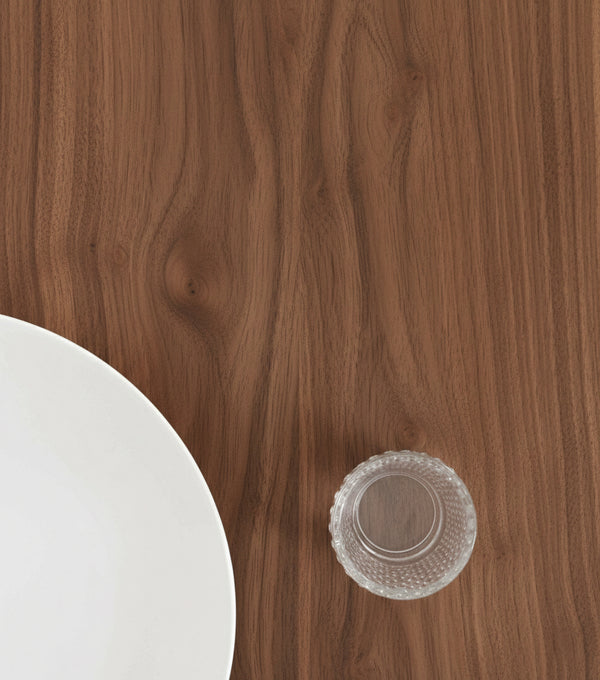 White plate and clear glass cup on a wooden table with visible grain patterns.