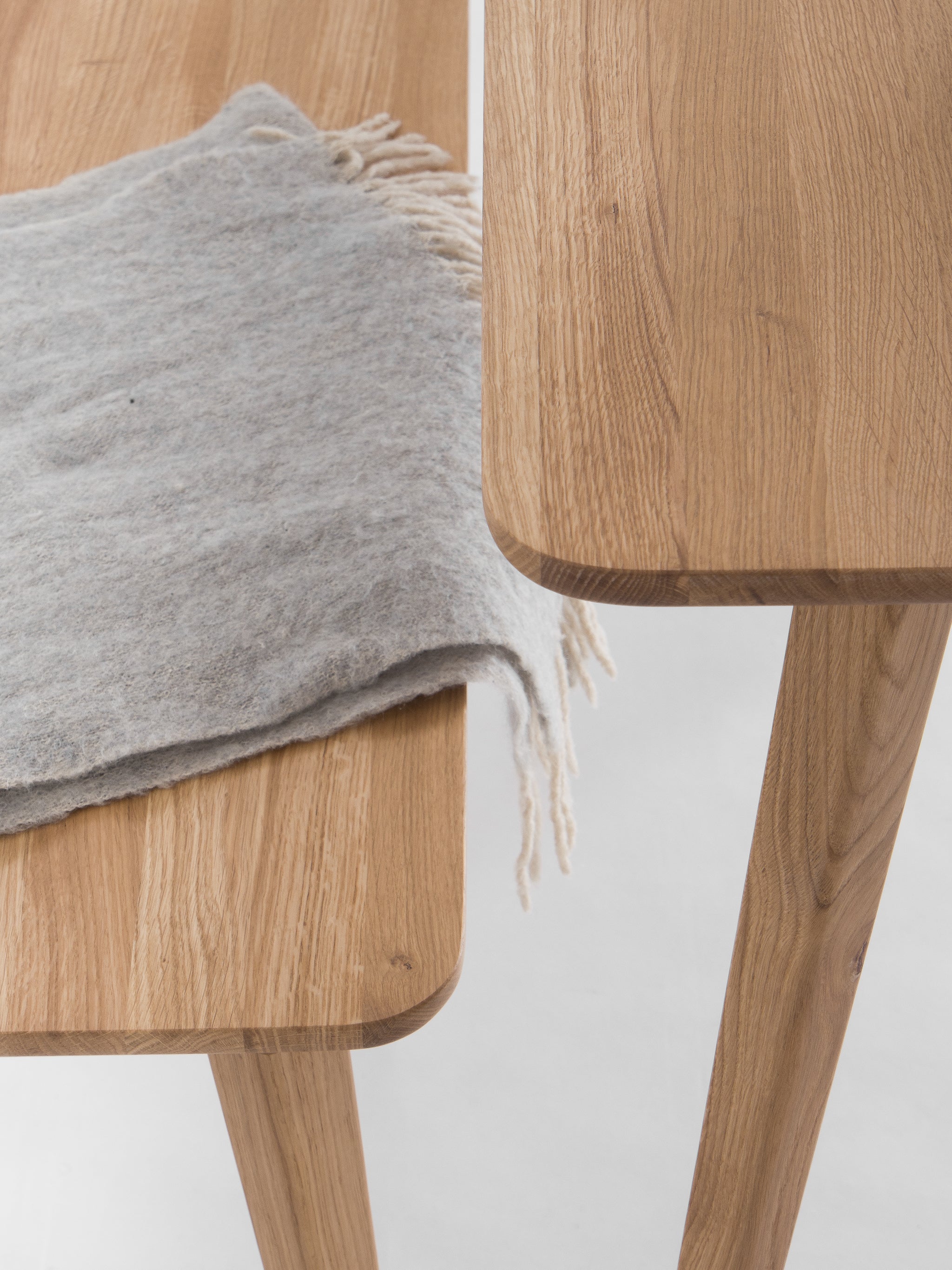 Wooden table and bench corner with a gray fringed blanket.