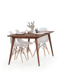 YRKE extendable table in solid American walnut, extended, angled view with white chairs, plates and eucalyptus