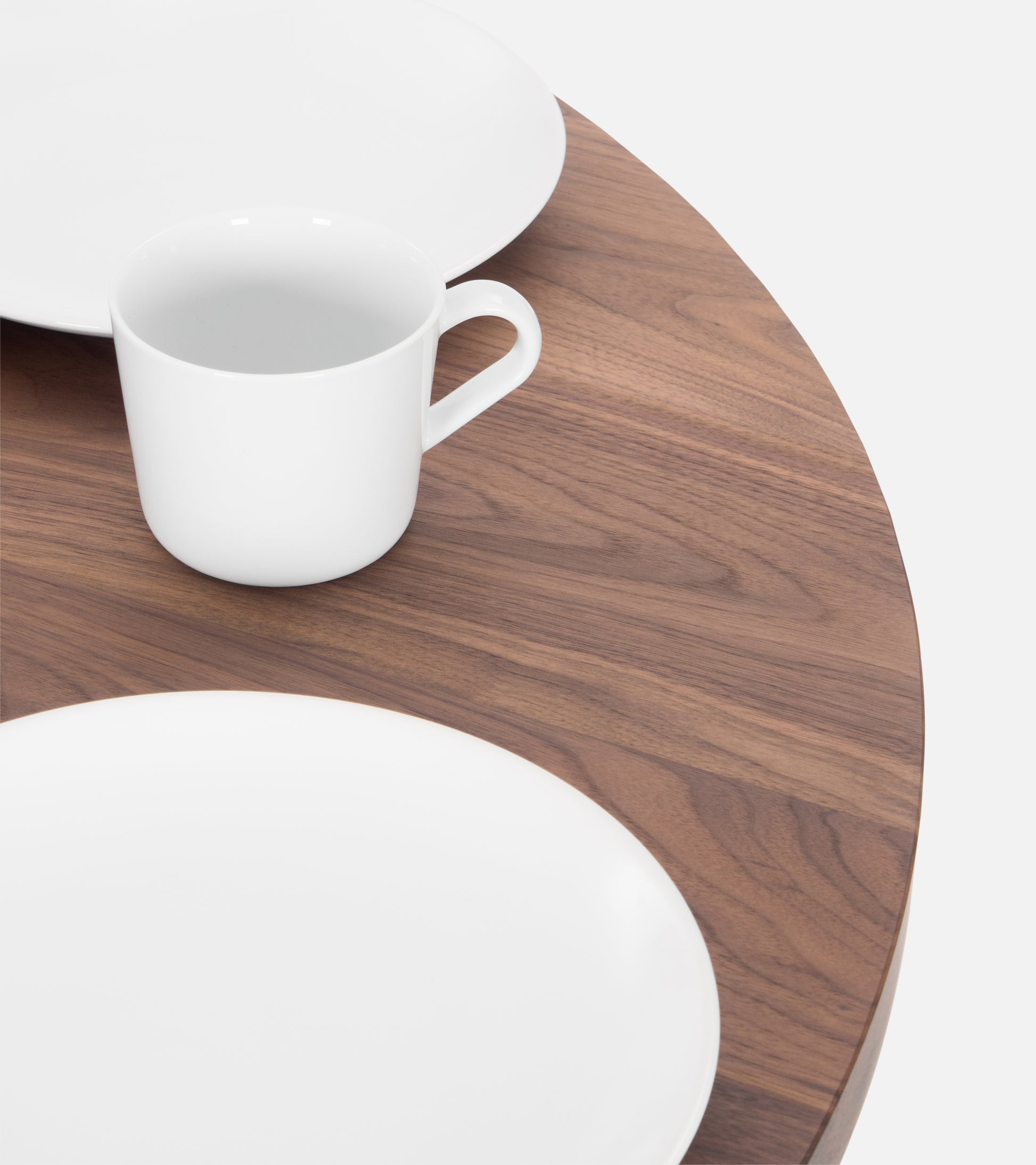 A white cup and two white plates on a wooden table.