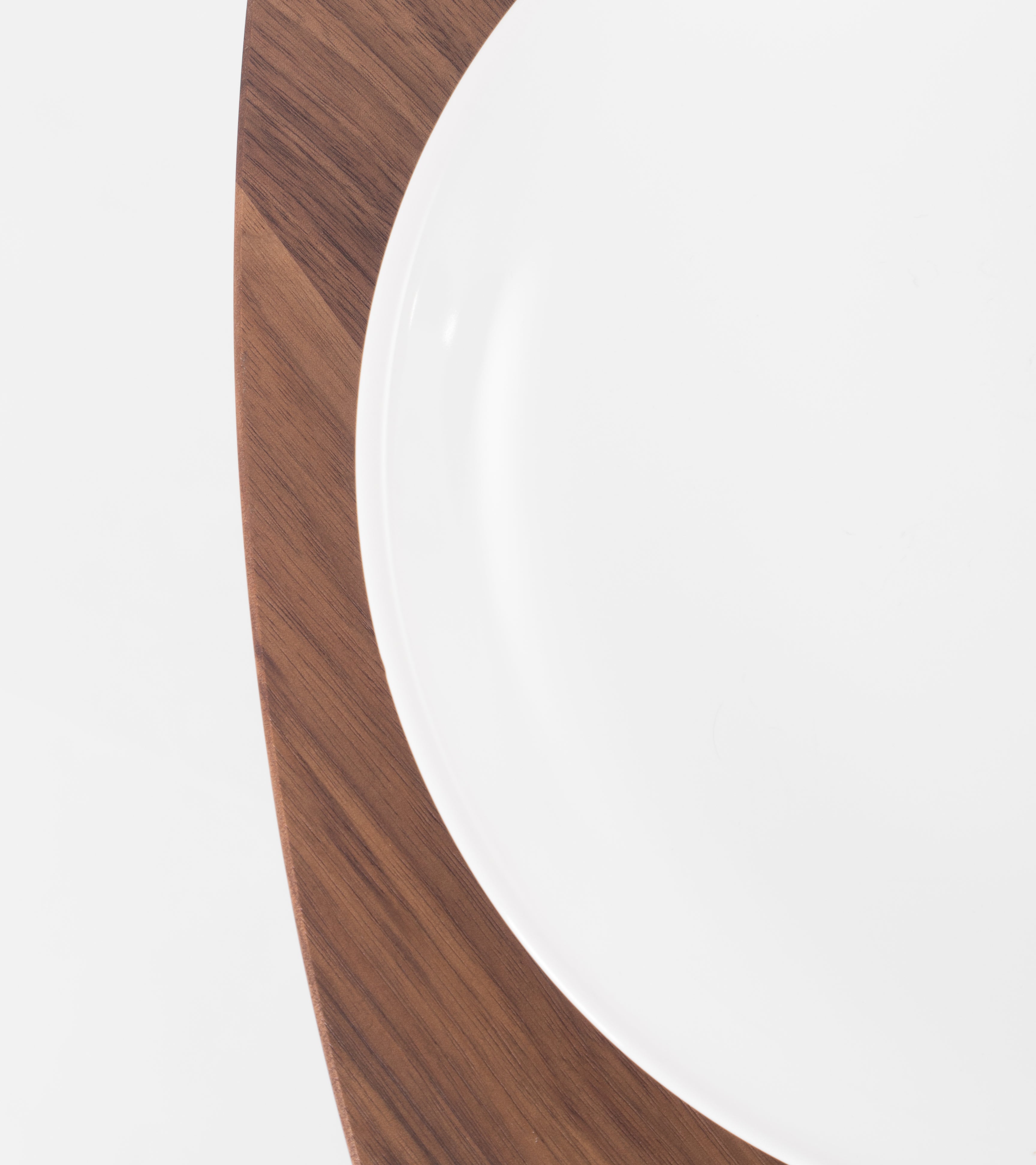 Close-up of a white plate on a wooden surface, both shown in partial view.