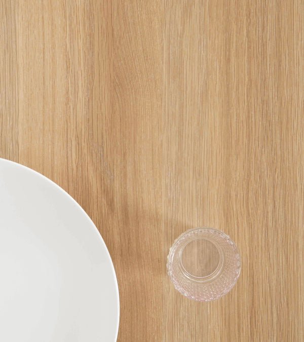 A white plate and a small glass on a wooden surface.