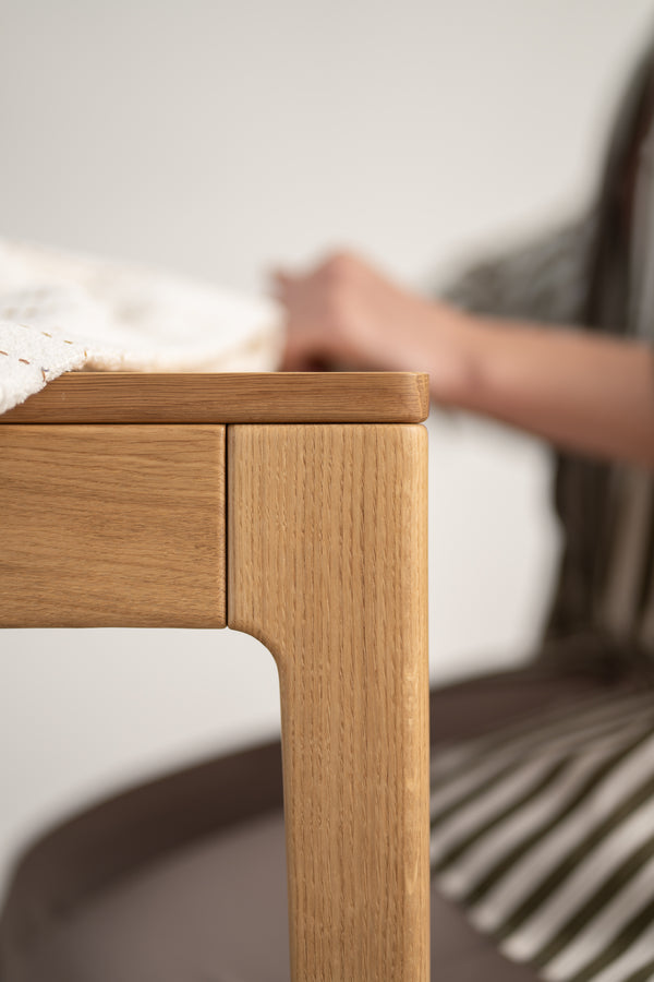Close-up of a wooden table edge with a partially visible person in the background.