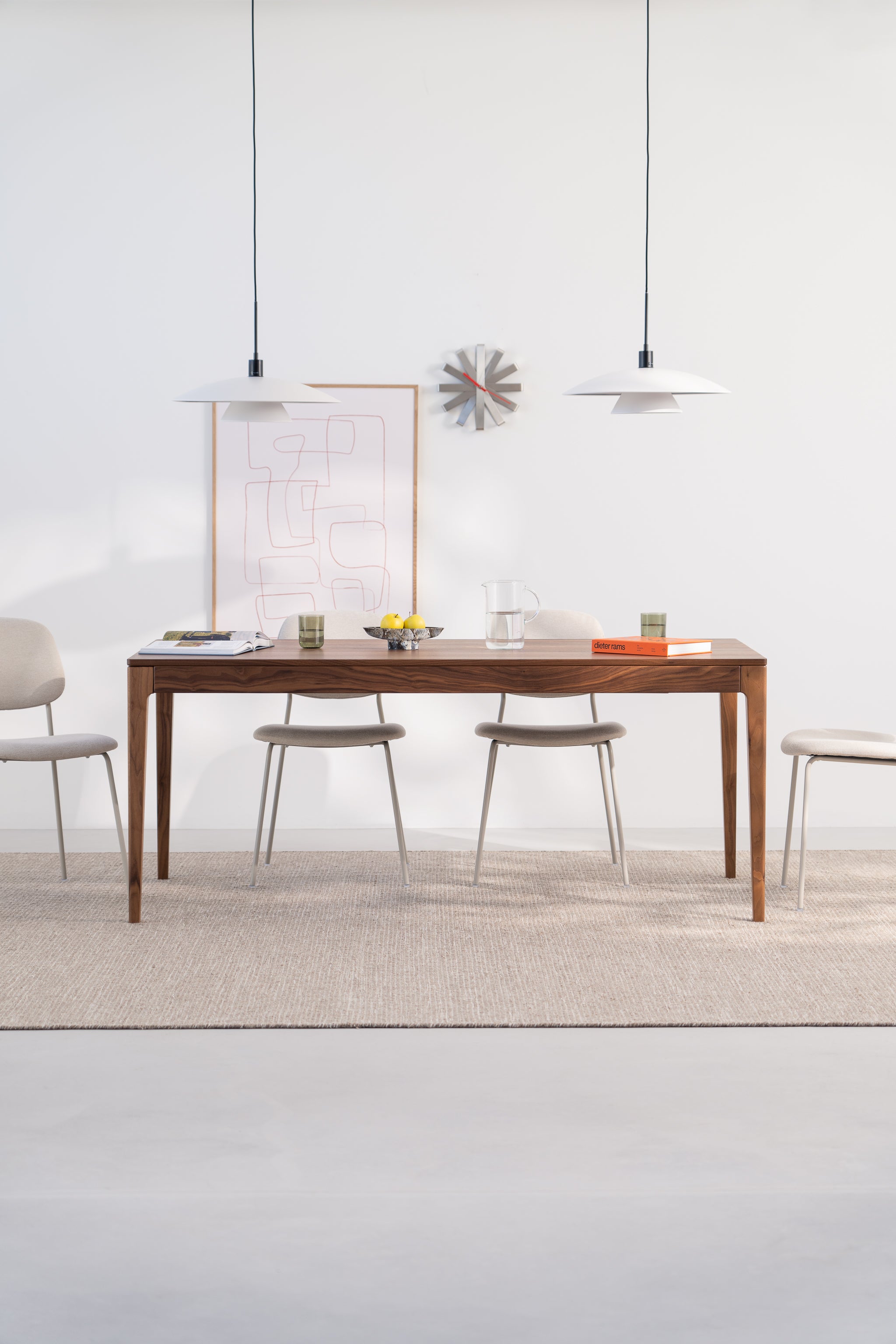 Minimalist dining area with a wooden table, chairs, pendant lights, and wall art.