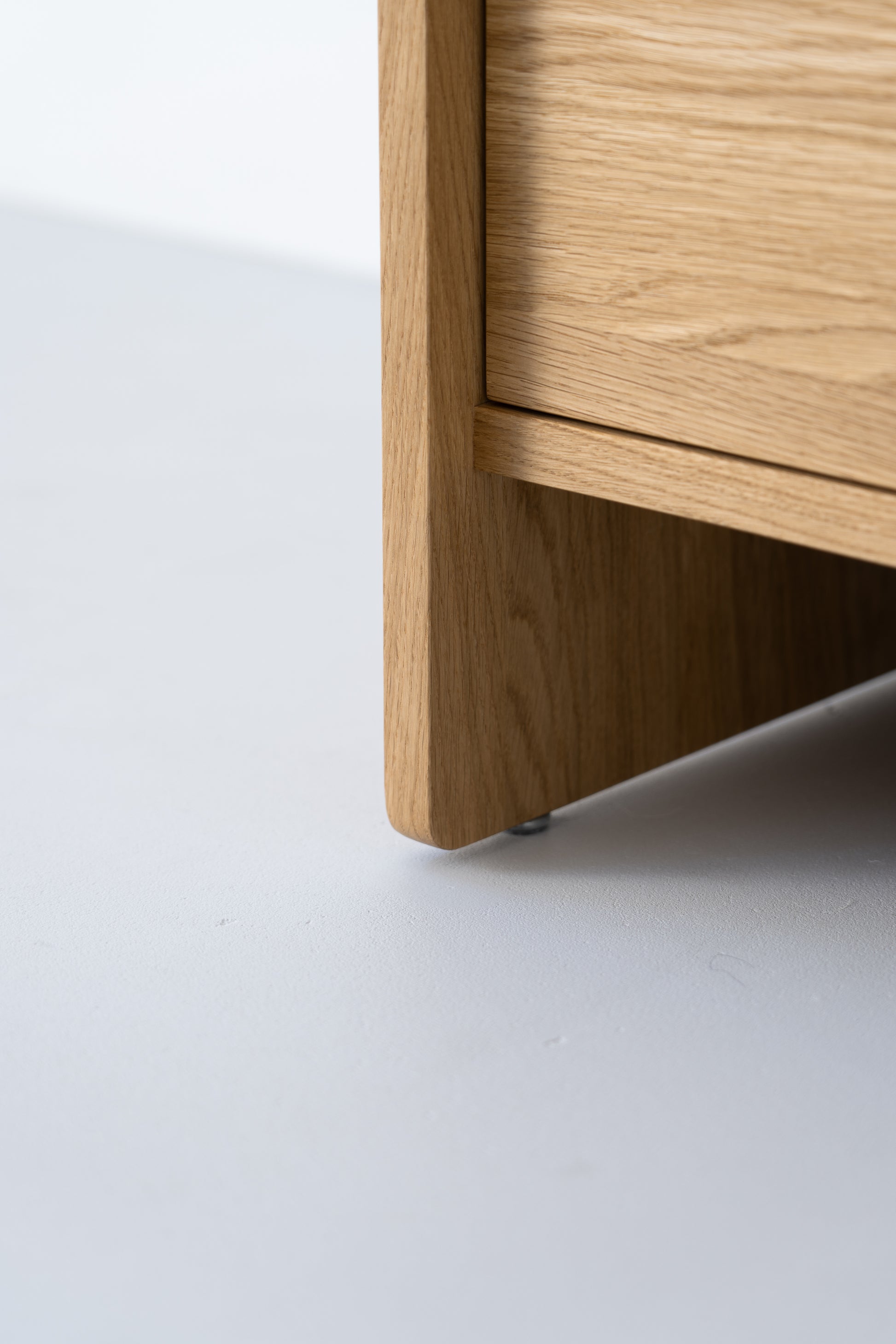 Close-up of a wooden furniture leg on a light-colored floor.