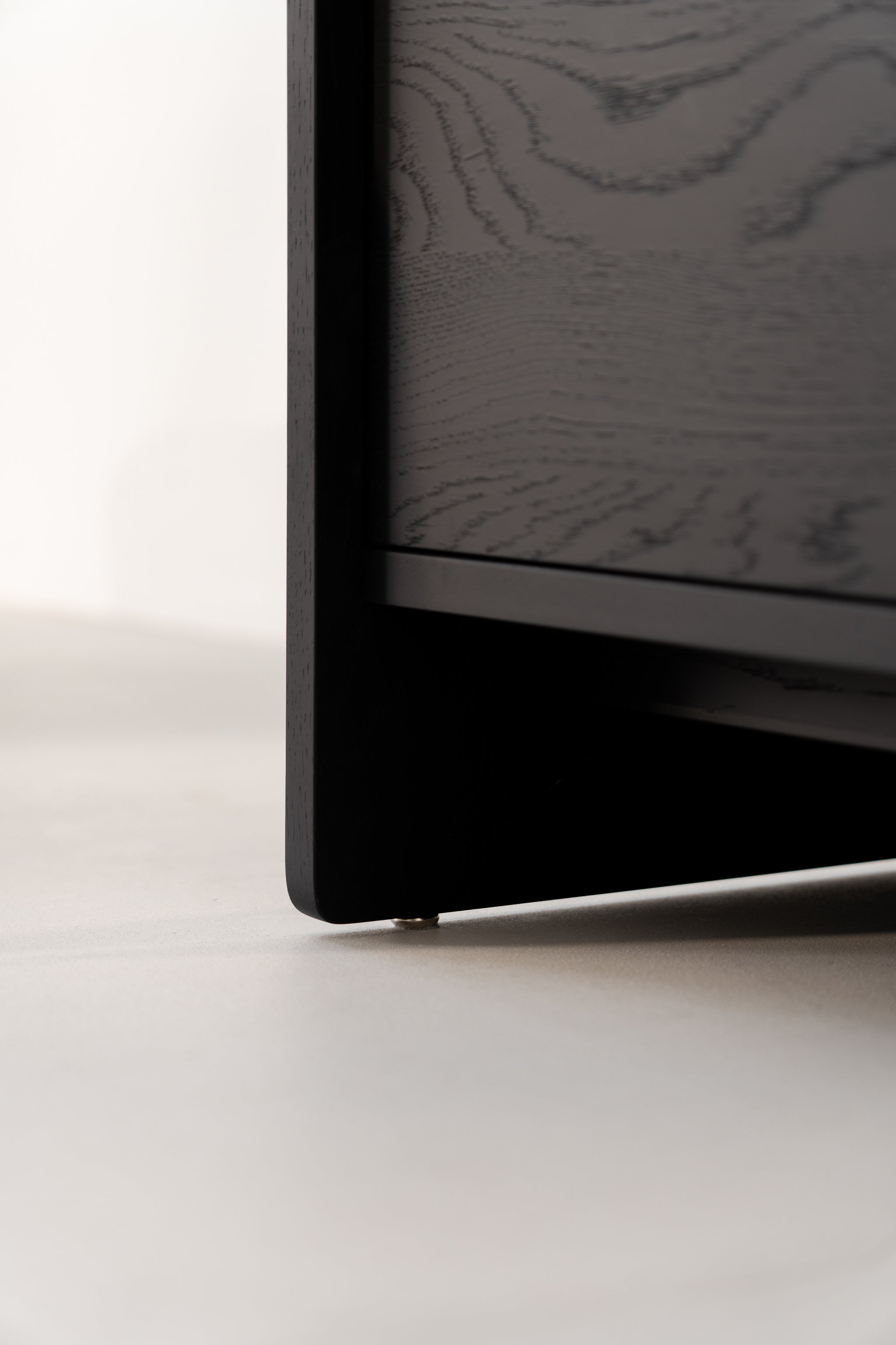 Close-up of a black wooden corner, focusing on floor surface with visible wood grain texture.