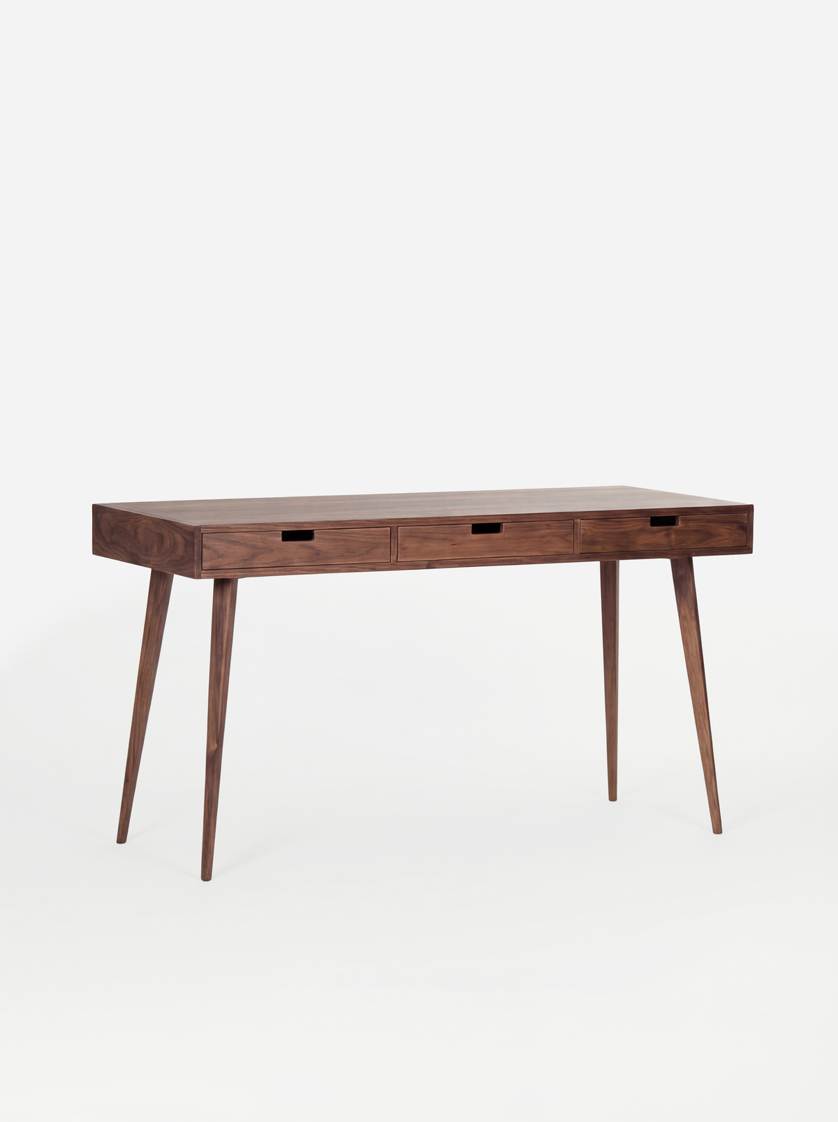 HEIM 140 desk in walnut wood, shown empty at an angle with three wooden drawer fronts on a white background