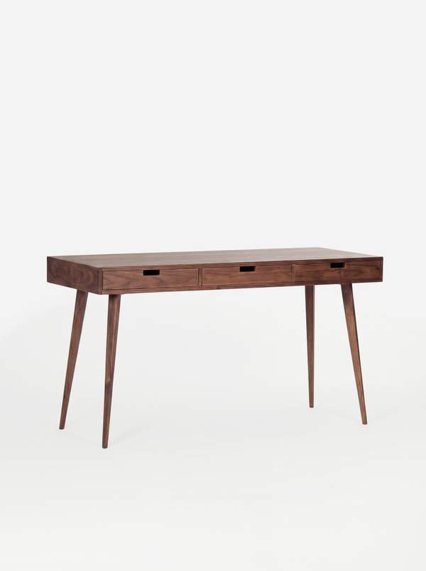 HEIM 140 desk in walnut wood, shown empty at an angle with three wooden drawer fronts on a white background