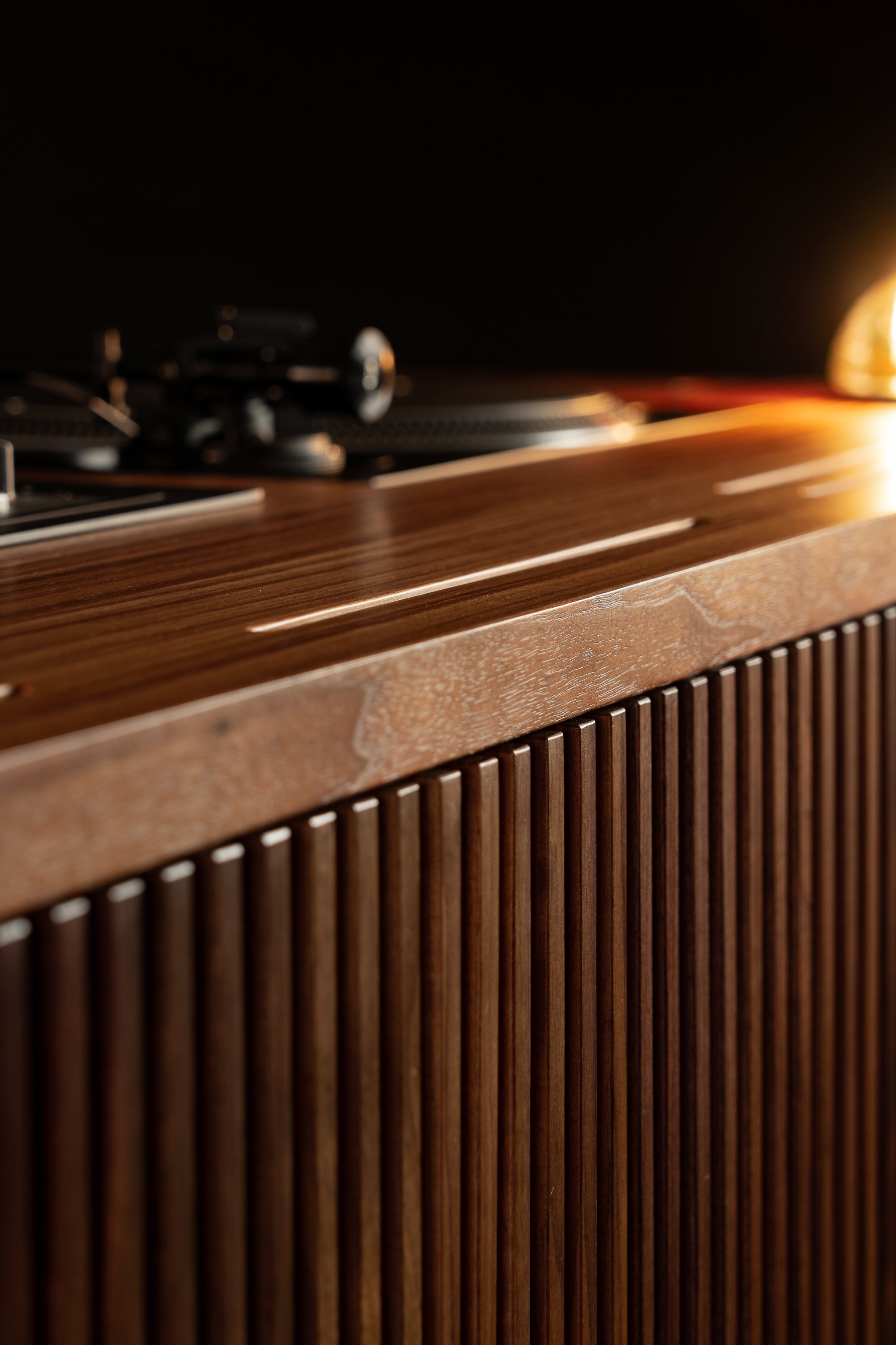Close-up of a wooden cabinet with vertical grooves, warm lighting creating a cozy ambiance.