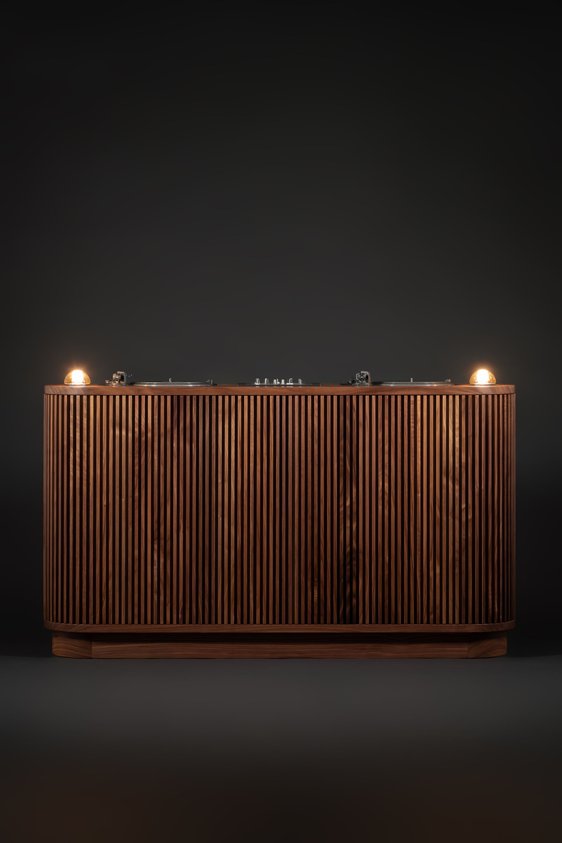 Wooden console with fluted panels and two illuminated bulbs on a dark background.