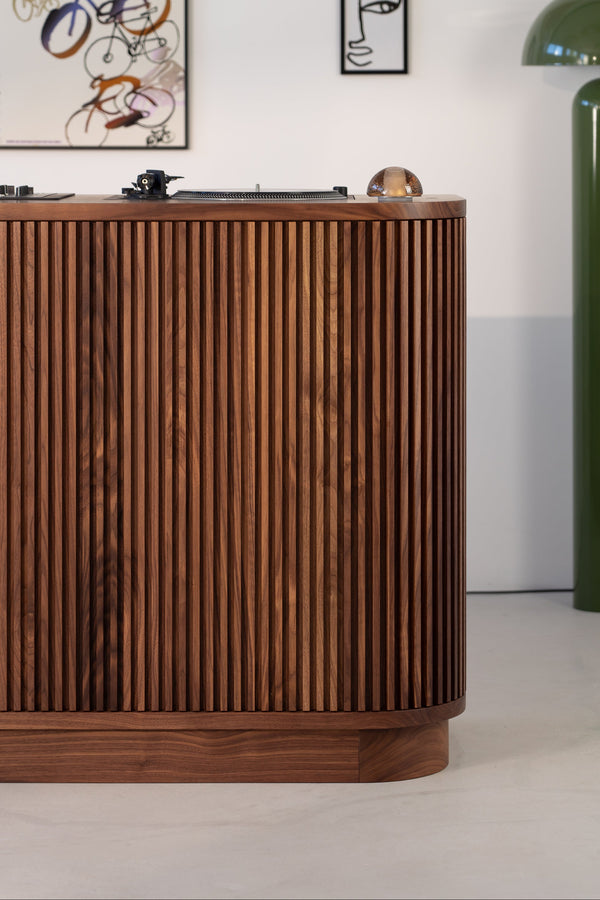 Wooden sideboard with vertical slats, green lamp, and two abstract wall art pieces.